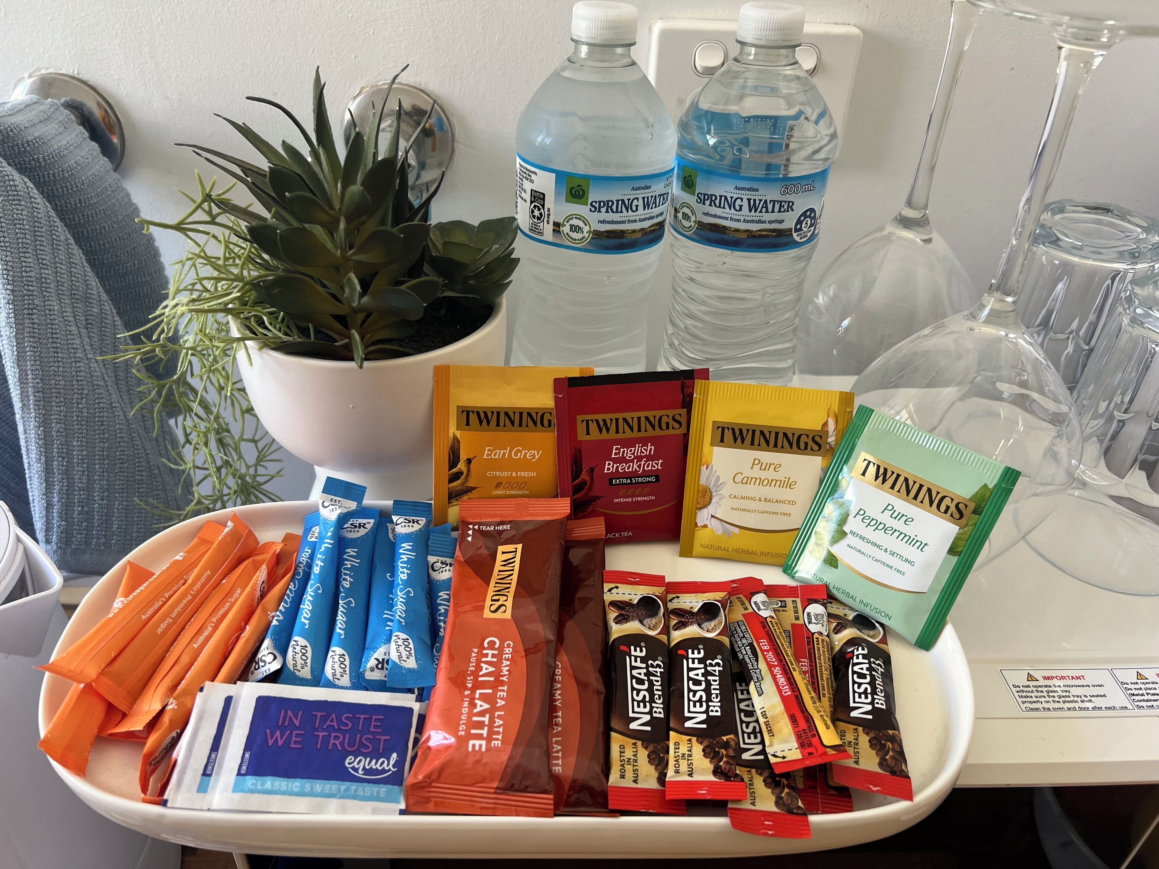 A tray with various tea bags, bottled water, and a potted plant.
