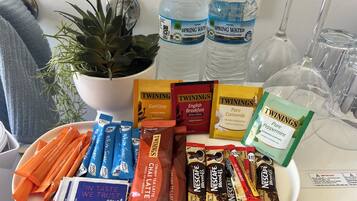 A tray with various tea bags, bottled water, and a potted plant.