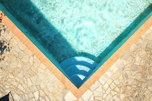 A swimming pool with a stone tile border and a clear blue water surface.