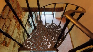 Een spiraaltrap met versierde metalen leuningen en een houten handrailing.