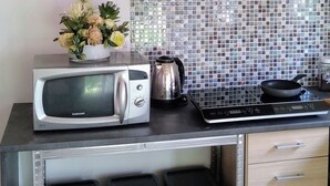 Una cocina con microondas, estufa, alacenas y salpicadero de azulejos.