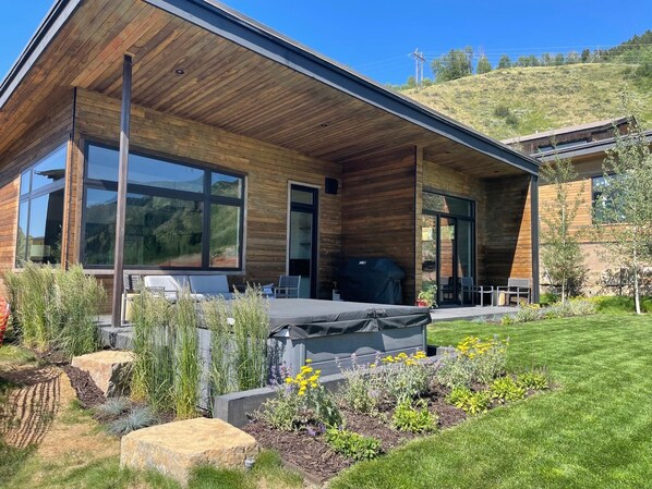 A modern house with large windows, a covered patio, and a well-maintained garden. - The Cabins At Snake River Sporting Club (Jackson)