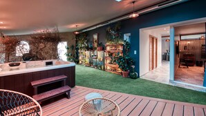 Ein moderner Außenbereich mit Whirlpool, Holzterrasse und Sitzgelegenheiten.