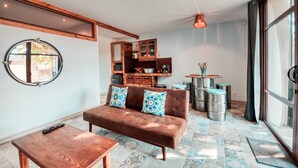 A cozy living area with a brown sofa, wooden coffee table, and a round mirror on the wall.