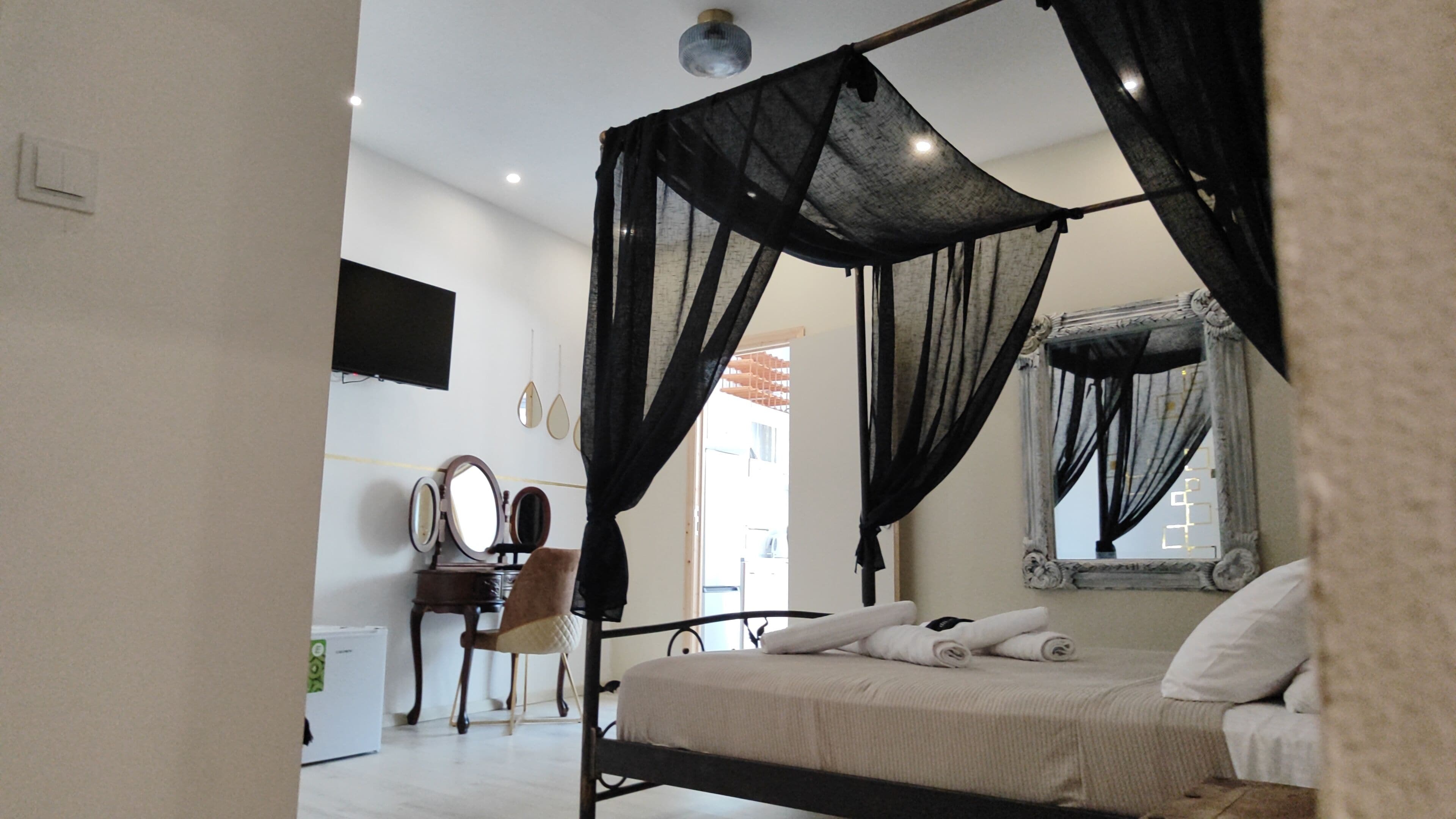 Un dormitorio con cama con dosel, tocador con espejo y un escritorio pequeño.