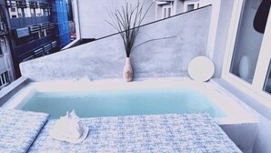 A modern indoor pool with a minimalist design, featuring a single lounge chair and a decorative vase. - Anchor Suites (Thessaloniki)