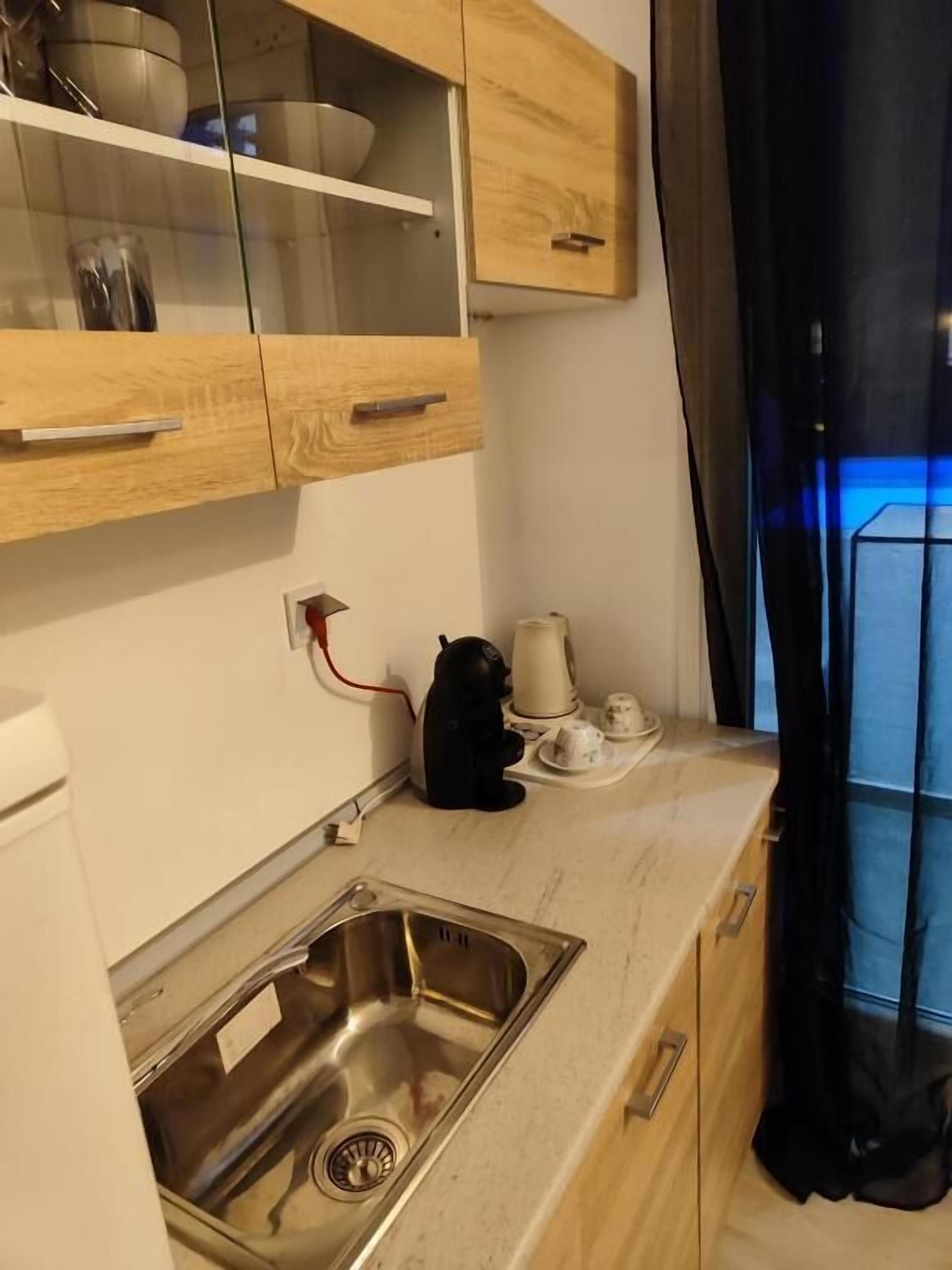 A compact kitchen with wooden cabinets, a stainless steel sink, and a coffee maker.