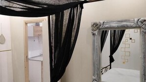 A room with a canopy bed, a large mirror, and a door leading to another room. - Anchor Suites (Thessaloniki)
