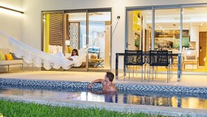 Zona de piscina con una hamaca, comedor y vistas al interior.