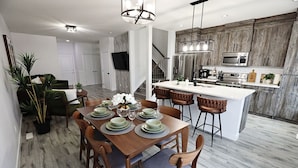 A modern kitchen with a central island, stainless steel appliances, and a wooden accent wall.