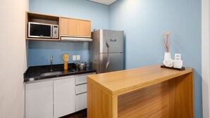 Eine kleine Küche mit Mikrowelle, Herd, Kühlschrank und einer Holzauskładfläche.
