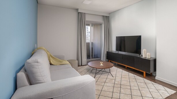 Ein modernes Wohnzimmer mit Sofa, Couchtisch, Fernseher und einer Schiebeglasdoor.
