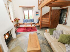 Uma sala de estar acolhedora com lareira, um banco de madeira, um sofá e uma escada.