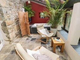 A cozy patio with wicker furniture, a wooden table, and potted plants.