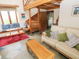 A cozy living room with a wooden bench, a sofa, and a coffee table. There is a staircase leading to another room.