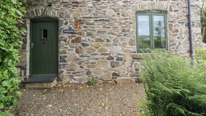 Un edificio in pietra con una porta verde e una finestra.