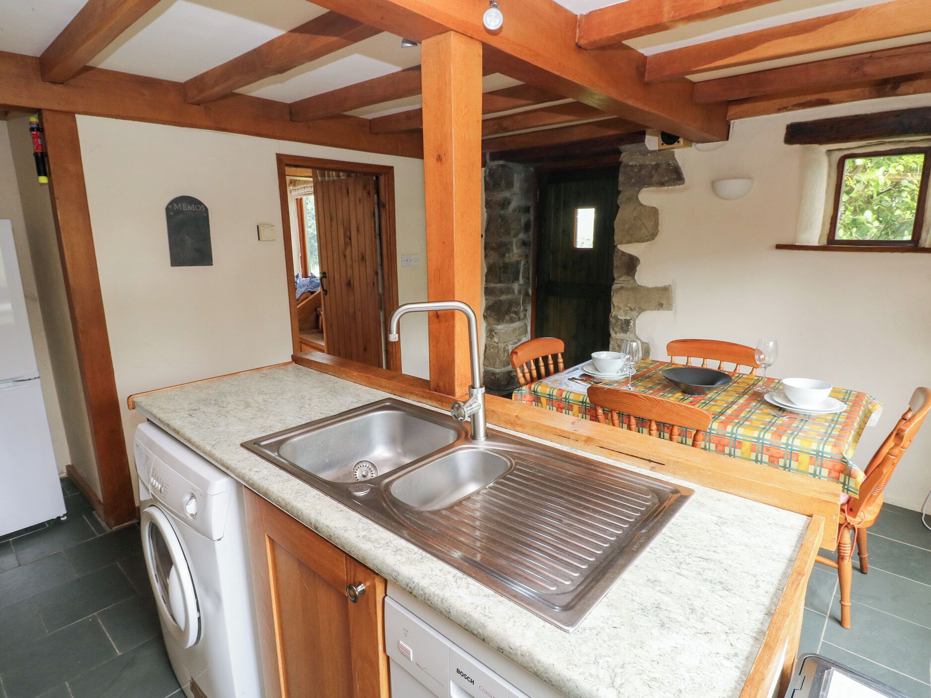 A compact kitchen with a built-in washing machine, a sink, and a dining area with a table and chairs.