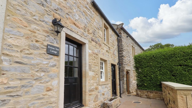 A stone cottage with a black door and a sign reading "Rowan Tree Cottage." - Rowan Tree Cottage (Skipton)