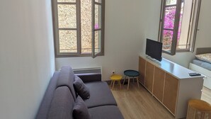 A modern living room with a large sofa, a TV, and a small table. - Apartment Sète centre-ville (Sète)