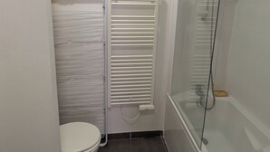 A small bathroom with a toilet, a glass shower enclosure, and a towel rack. - Apartment Sète centre-ville (Sète)