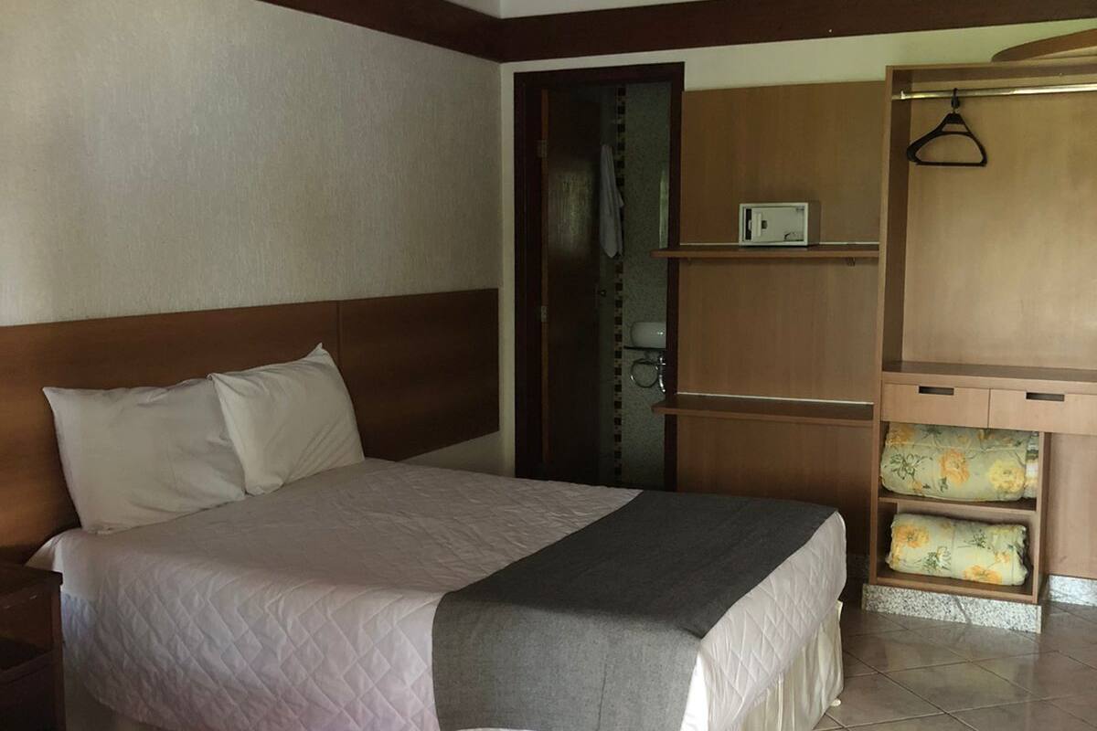 Een slaapkamer met een bed, een plafondventilator, een kledingkast en een zichtbare badkamer door een geopende deur.