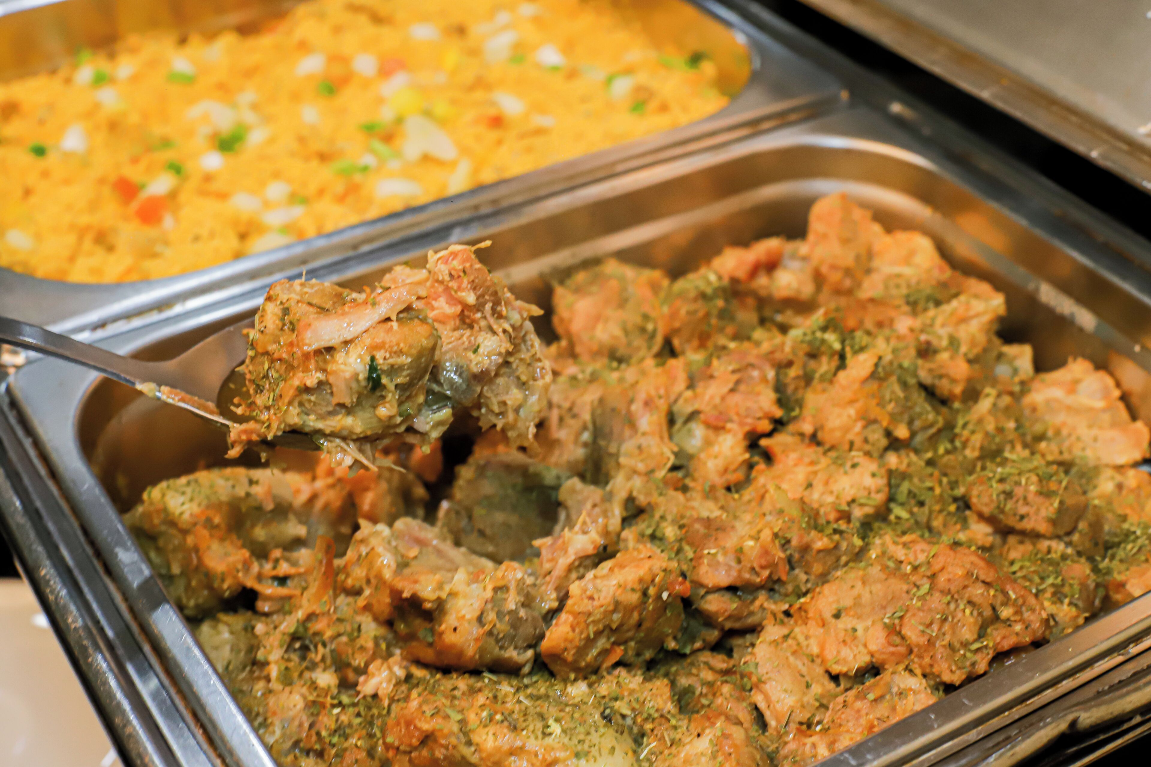 A buffet with various dishes, including a section with a green herb sauce and another with a yellow rice dish.