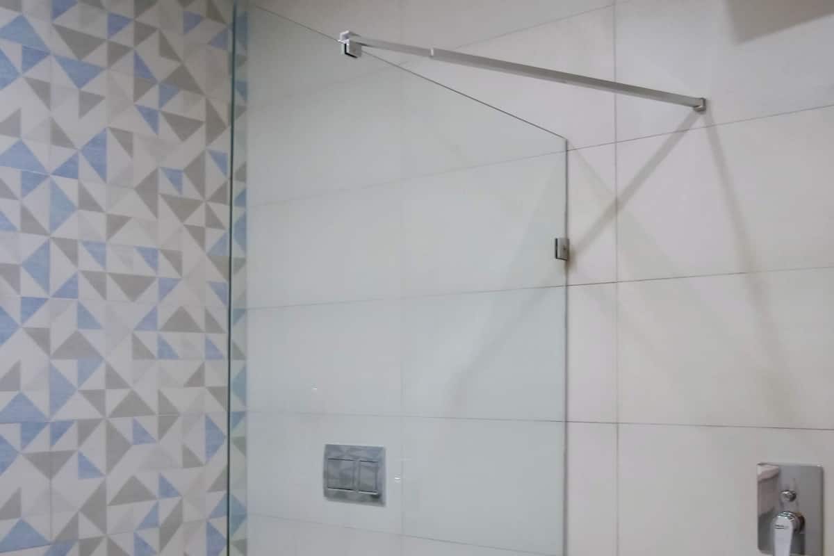 A bathroom with a glass-enclosed shower, a toilet, and a towel rack.