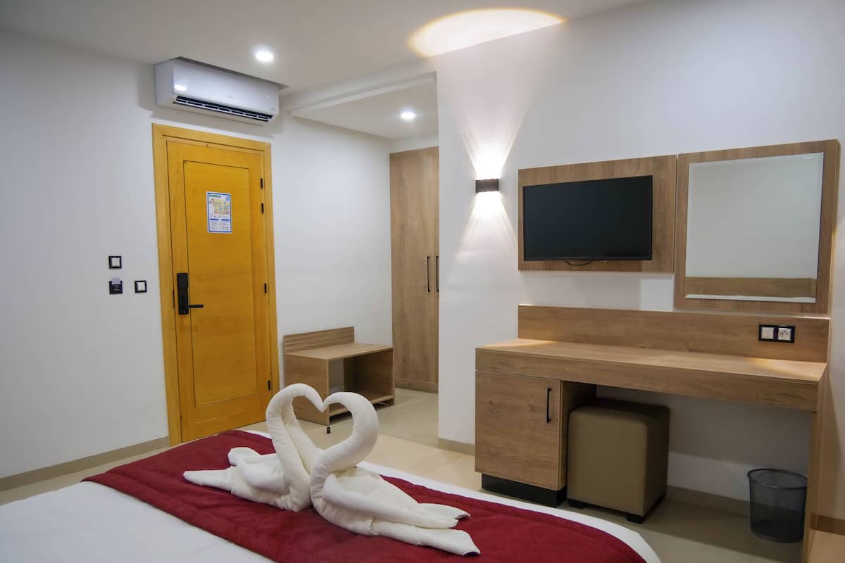 A hotel room with a bed, a desk, a television, and a mirror.