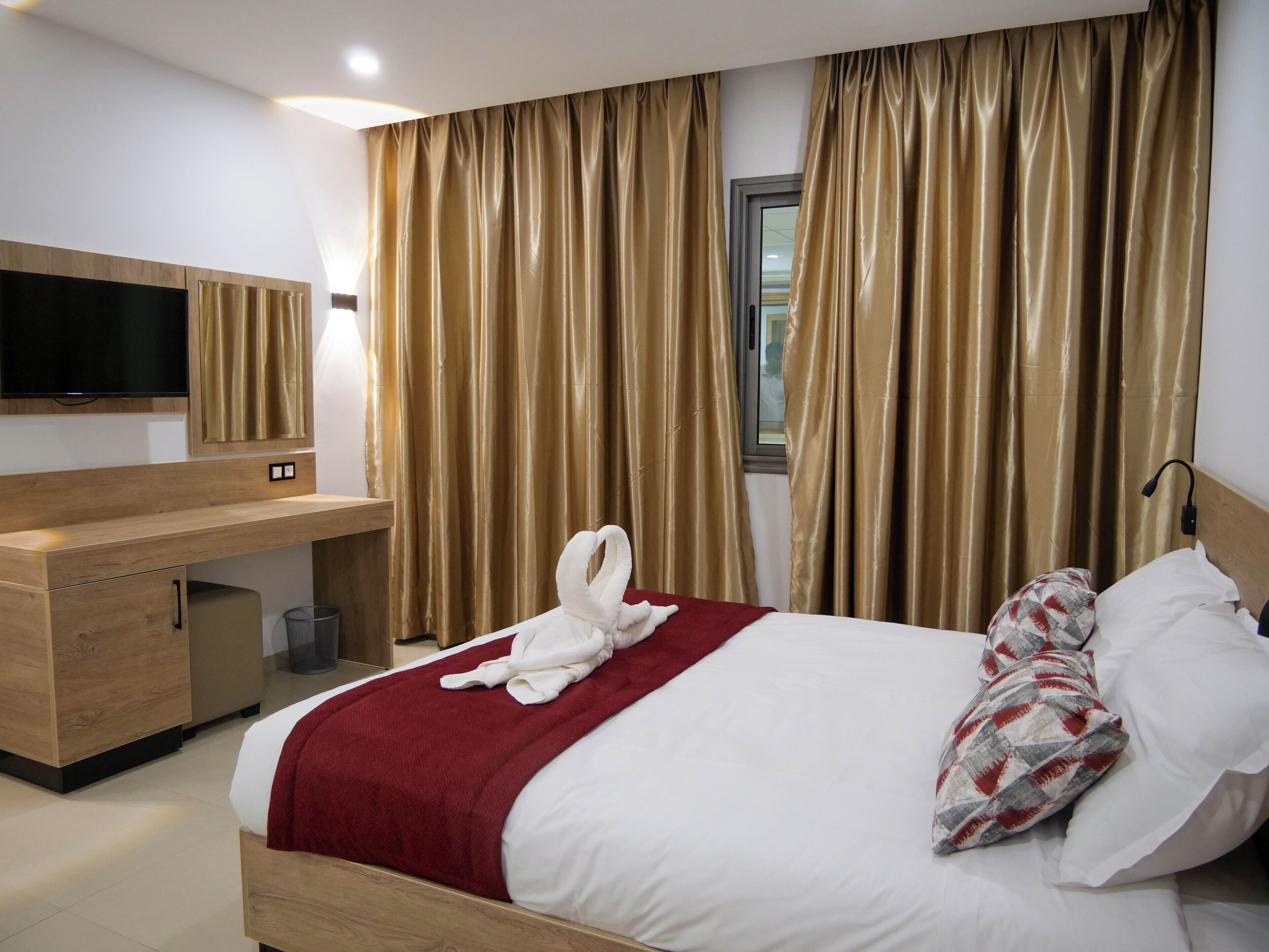 Ein Hotelzimmer mit Bett, Schreibtisch, Fernseher und Vorhängen.