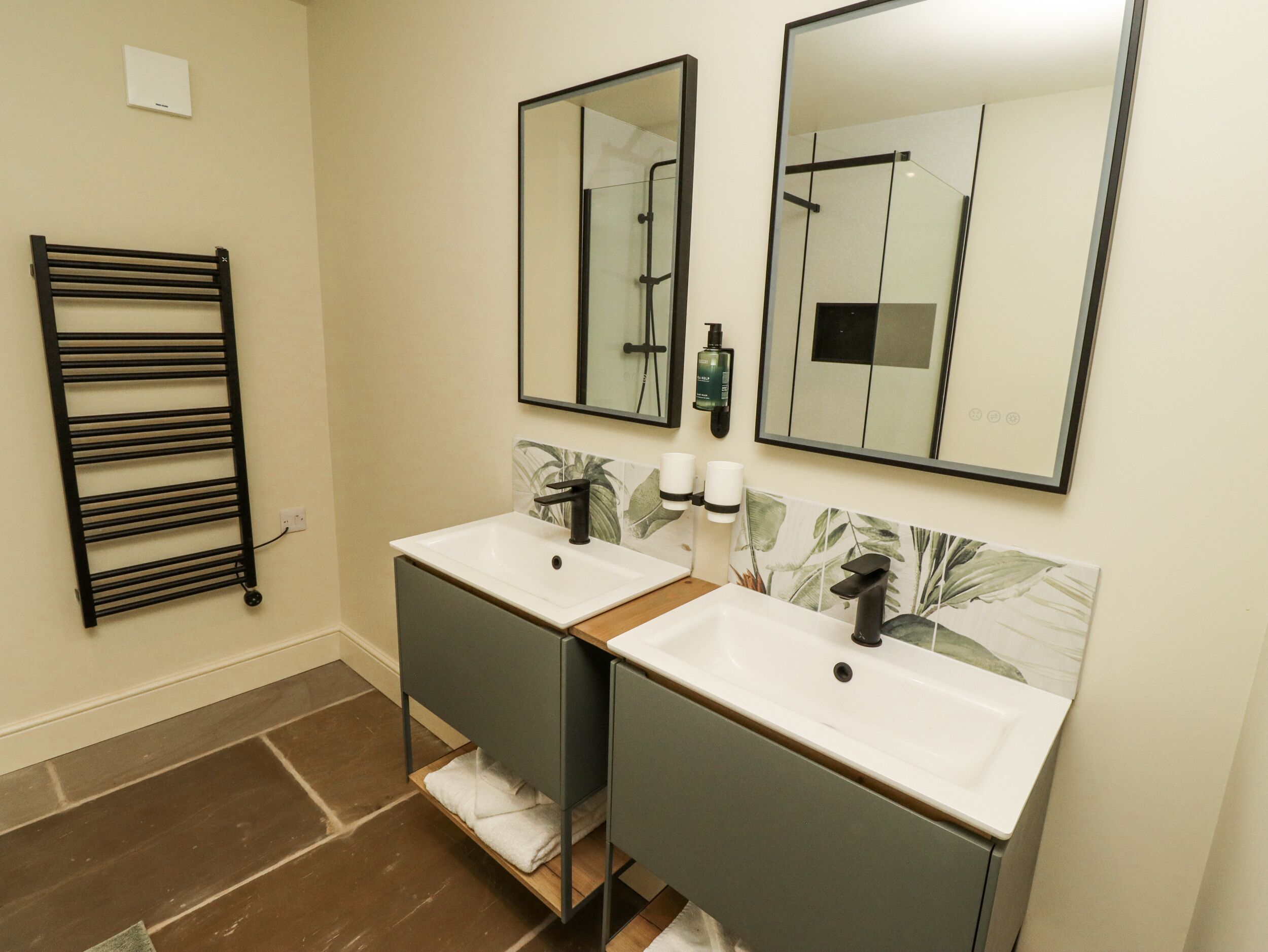 Un bagno con due lavandini, un portasciugamani e due specchi.