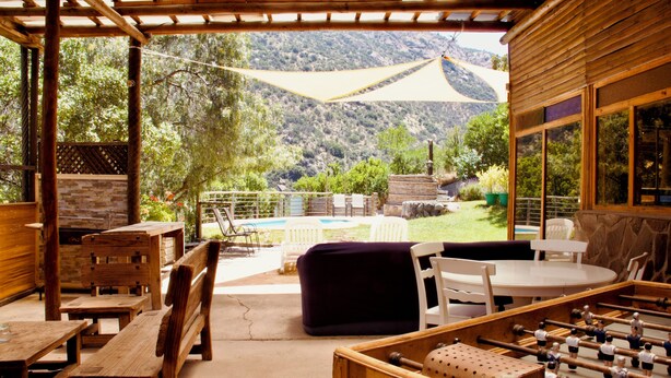 Une terrasse extérieure avec des meubles en bois, une table de baby-foot et une vue sur un paysage montagneux.