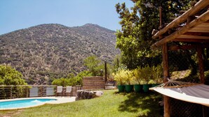 Un espace piscine avec vue sur une montagne, un hamac et une terrasse en bois.
