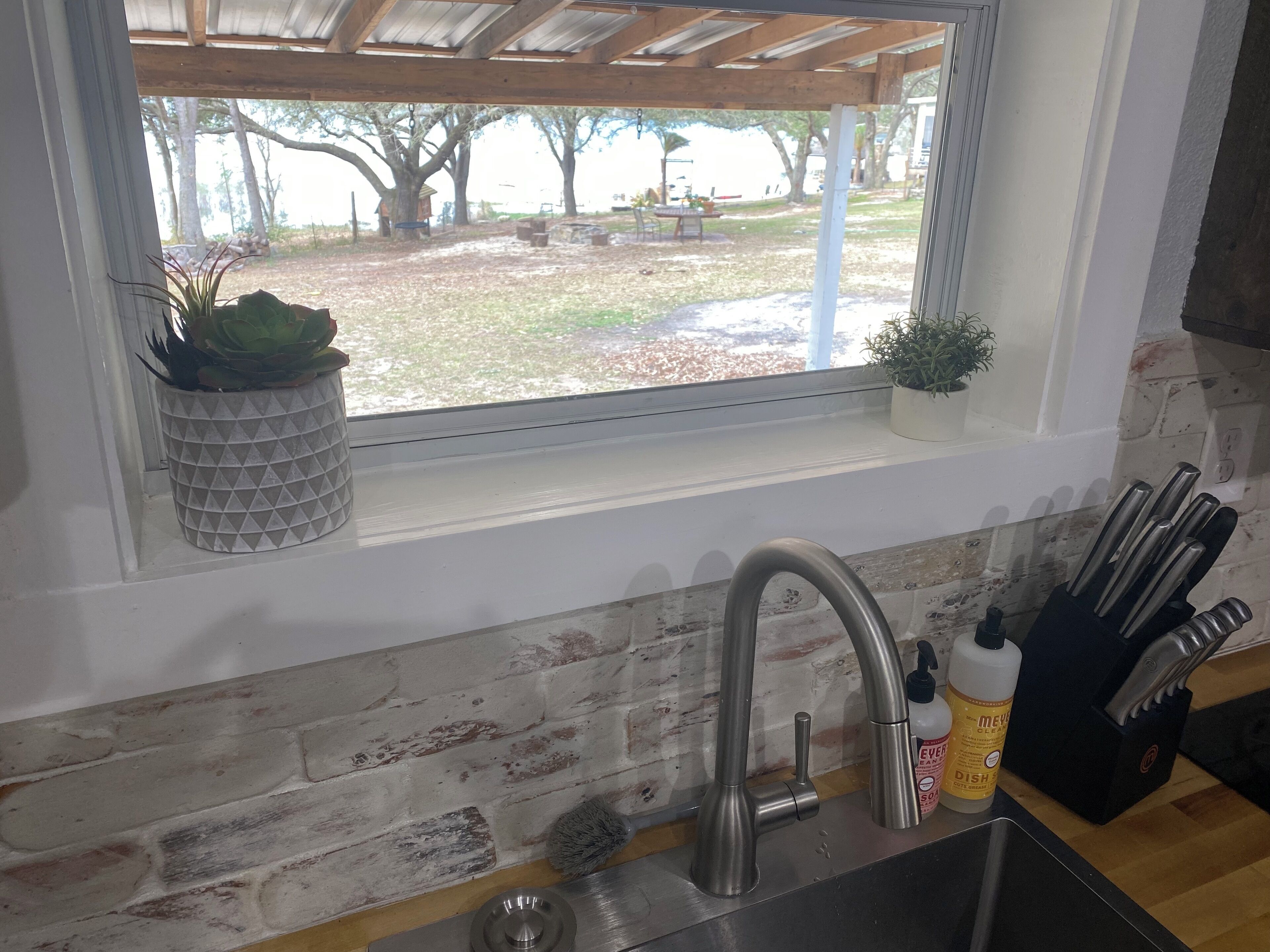 A kitchen with a window, a sink, and a brick wall.