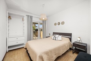 Une chambre avec un lit, une table de chevet, une armoire et un balcon avec vue.