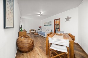 Un salon moderne avec une table à manger en bois, un canapé et un grand fauteuil en osier.
