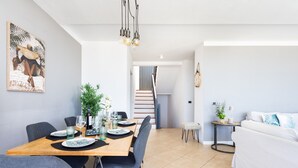 A modern dining area with a wooden table, chairs, and a staircase leading to another level. - Casa Uamisun with seaview & pool (Costa Adeje)