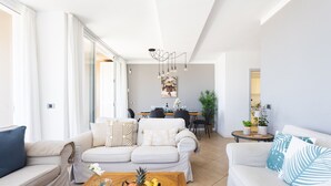 A spacious living room with a sofa set, a coffee table with fruit, and a dining area in the background. - Casa Uamisun with seaview & pool (Costa Adeje)