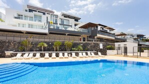 A modern hotel with a swimming pool, sun loungers, and a stone wall. - Casa Uamisun with seaview & pool (Costa Adeje)