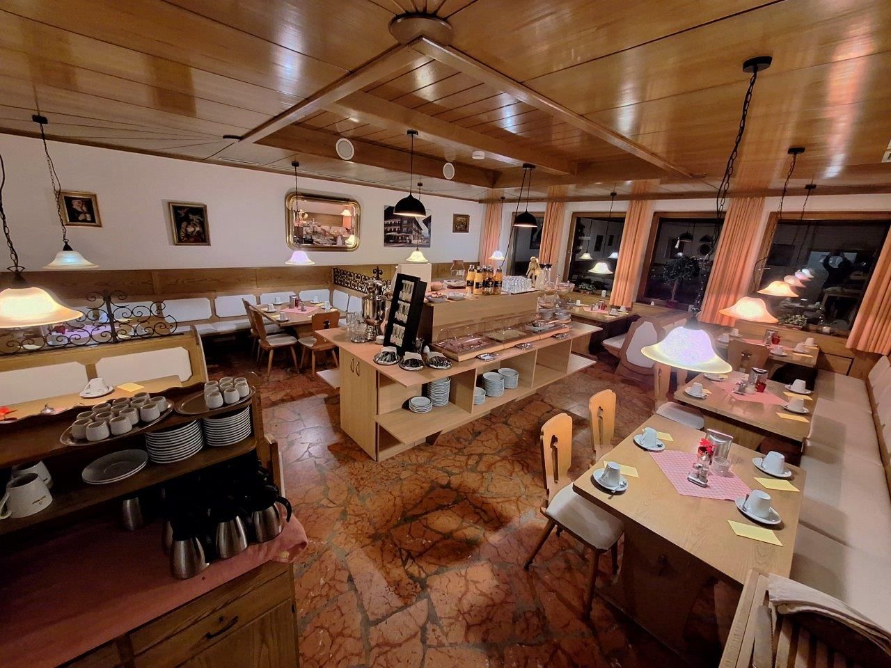 A restaurant with wooden interiors, multiple dining tables, and a central buffet area.
