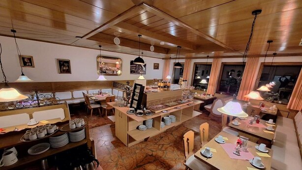 A restaurant with wooden interiors, multiple dining tables, and a central buffet area. - Hotel Löwen (Reit im Winkl)