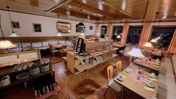 A restaurant with wooden interiors, multiple dining tables, and a central buffet area.