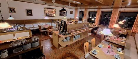 A restaurant with wooden interiors, multiple dining tables, and a central buffet area.