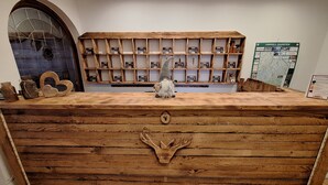 Un mostrador de recepción de madera con diseño rústico, una figura de gnomo y un mapa en la pared.