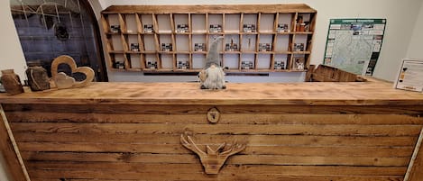 Un comptoir d’accueil en bois, de style rustique, orné d’une figurine de gnome et d’une carte accrochée au mur.