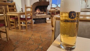 Un verre de bière Löwenbräu dans un cadre chaleureux et rustique, avec des meubles en bois et une cheminée.