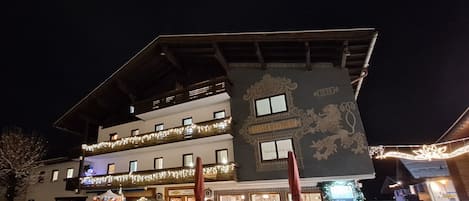 Un hotel con balcón, un árbol de Navidad y mobiliario de exterior.