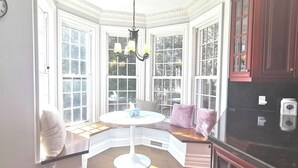 Eine Erkerbänkchen-Ecke mit rundem Tisch, gepolsterten Bänken und einer Chandelier.