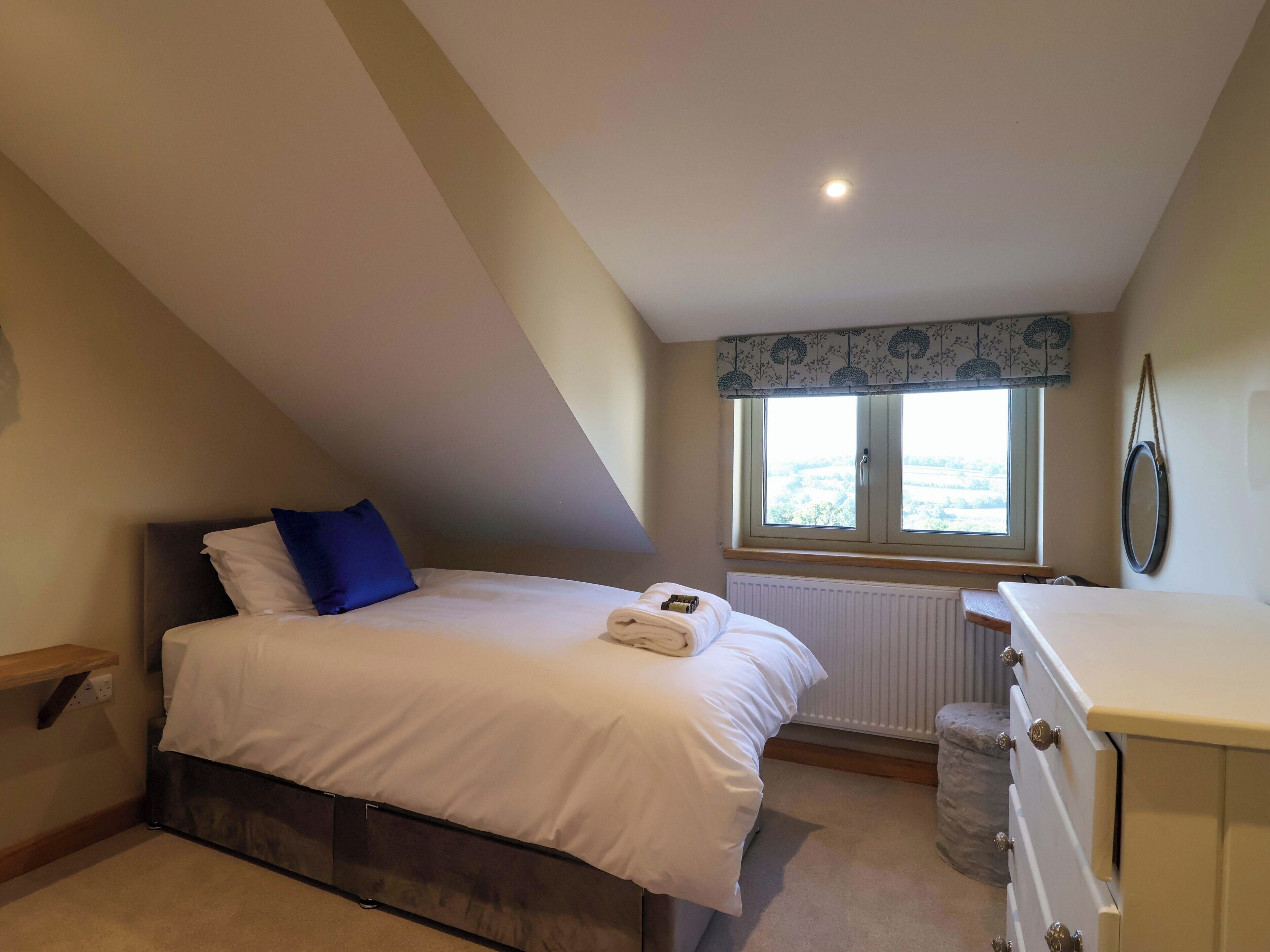 A bedroom with a bed, a window with a view, a radiator, and a dresser.