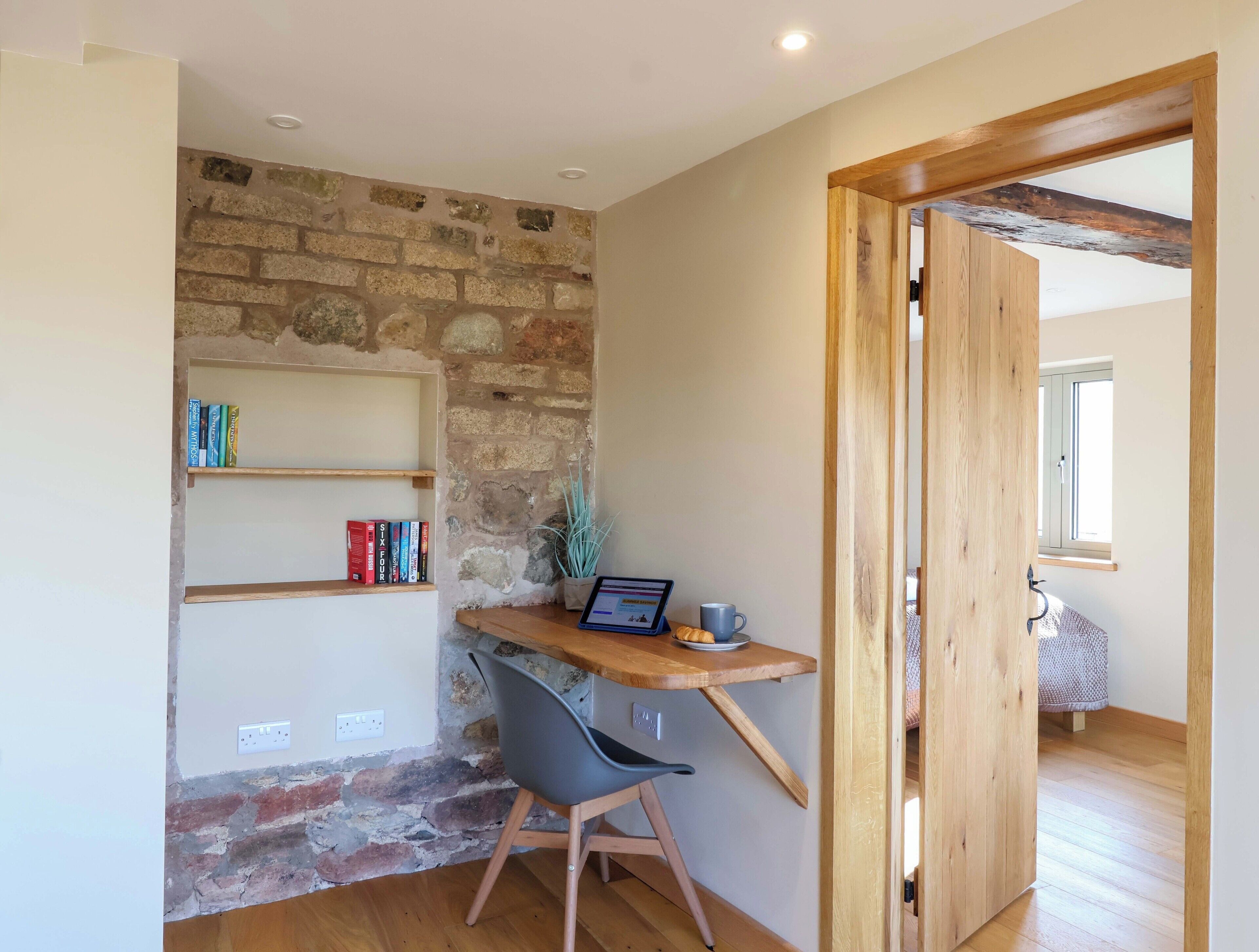 Un'area studio con una scrivania in legno, scaffali e una sedia.
