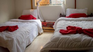 A room with two beds, each with white bedding and red pillows. There is a window with a metal grill and a curtain. - Msovi House - Standard Twin Room (Arusha)